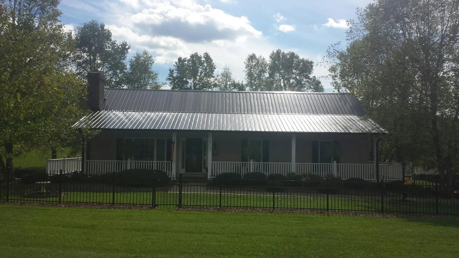 Gray metal roof on a brick ranch with a full width front porch — Gutter Guard Installation work by our crew in Wessington Springs