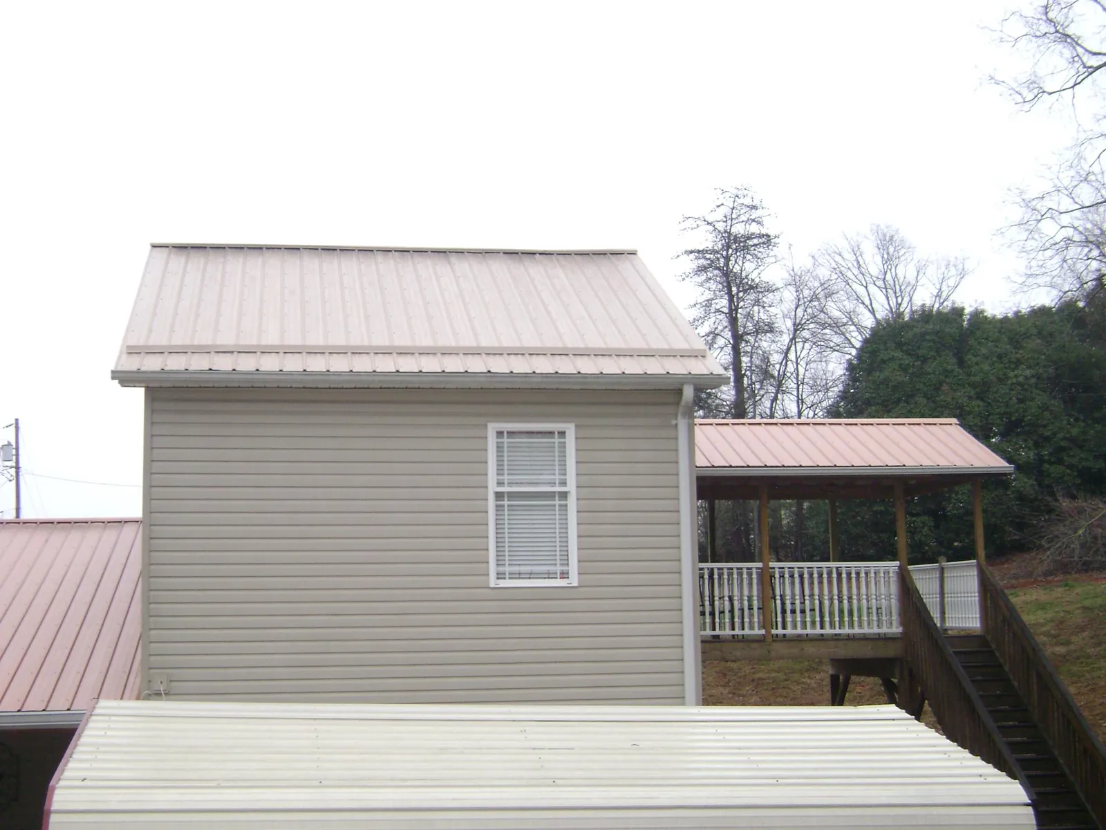 Tan metal roofs on a two story addition and attached porch, from a Roof Replacement job in Wessington Springs
